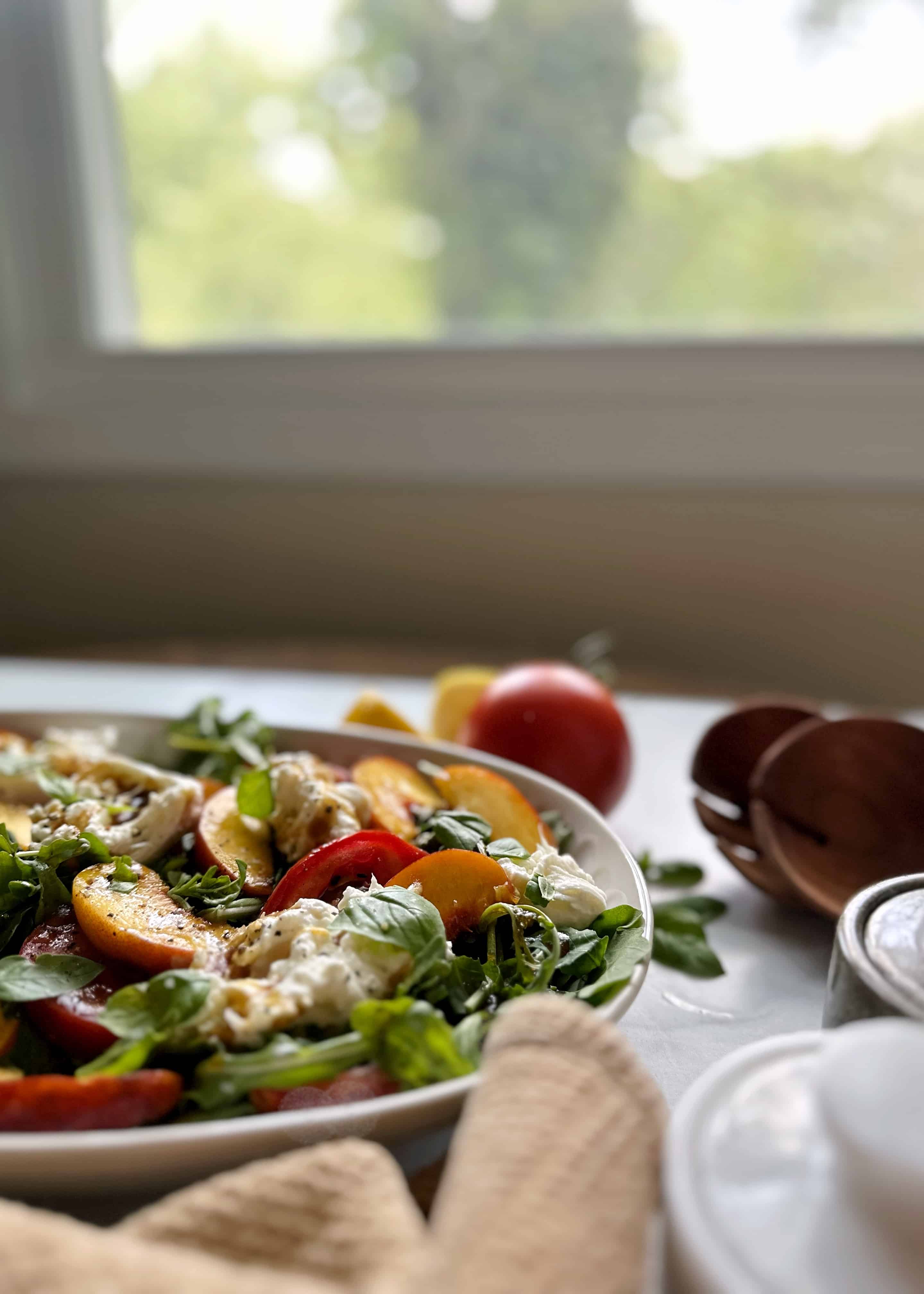 peach tomato burrata salad by a kitchen windowl