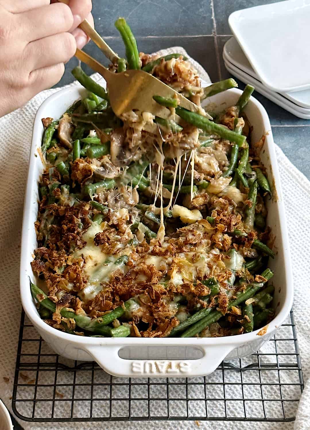 cheesy green bean casserole with gold silverware and cheese pull