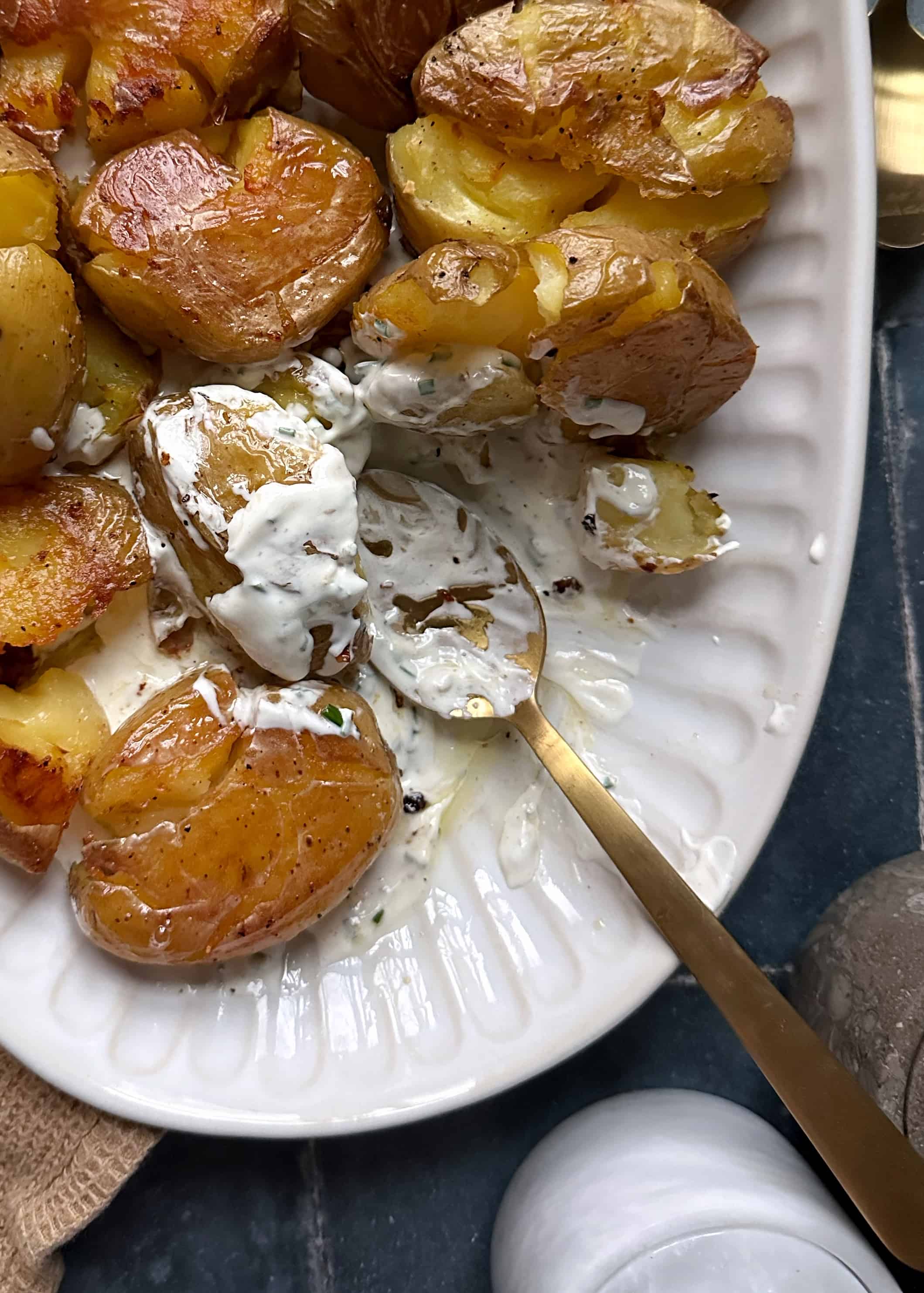 crispy garlic smashed potatoes with chive sauce on gold spoon
