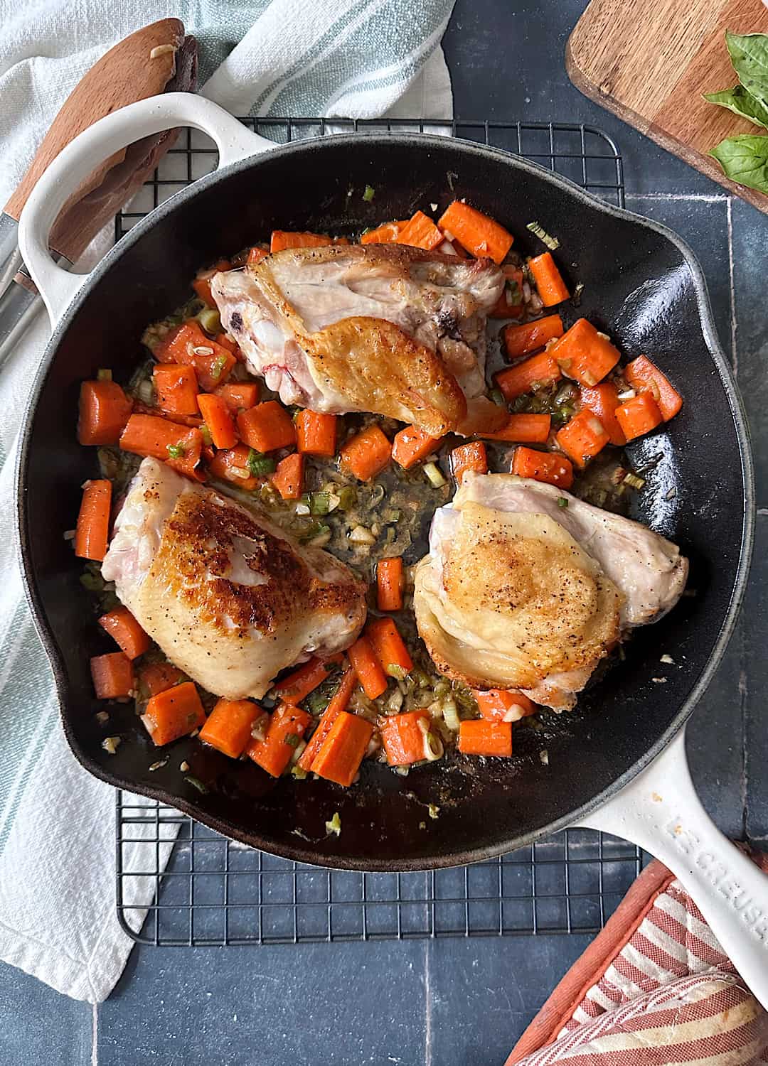 crispy chicken thighs with sauteed carrots in frying pan