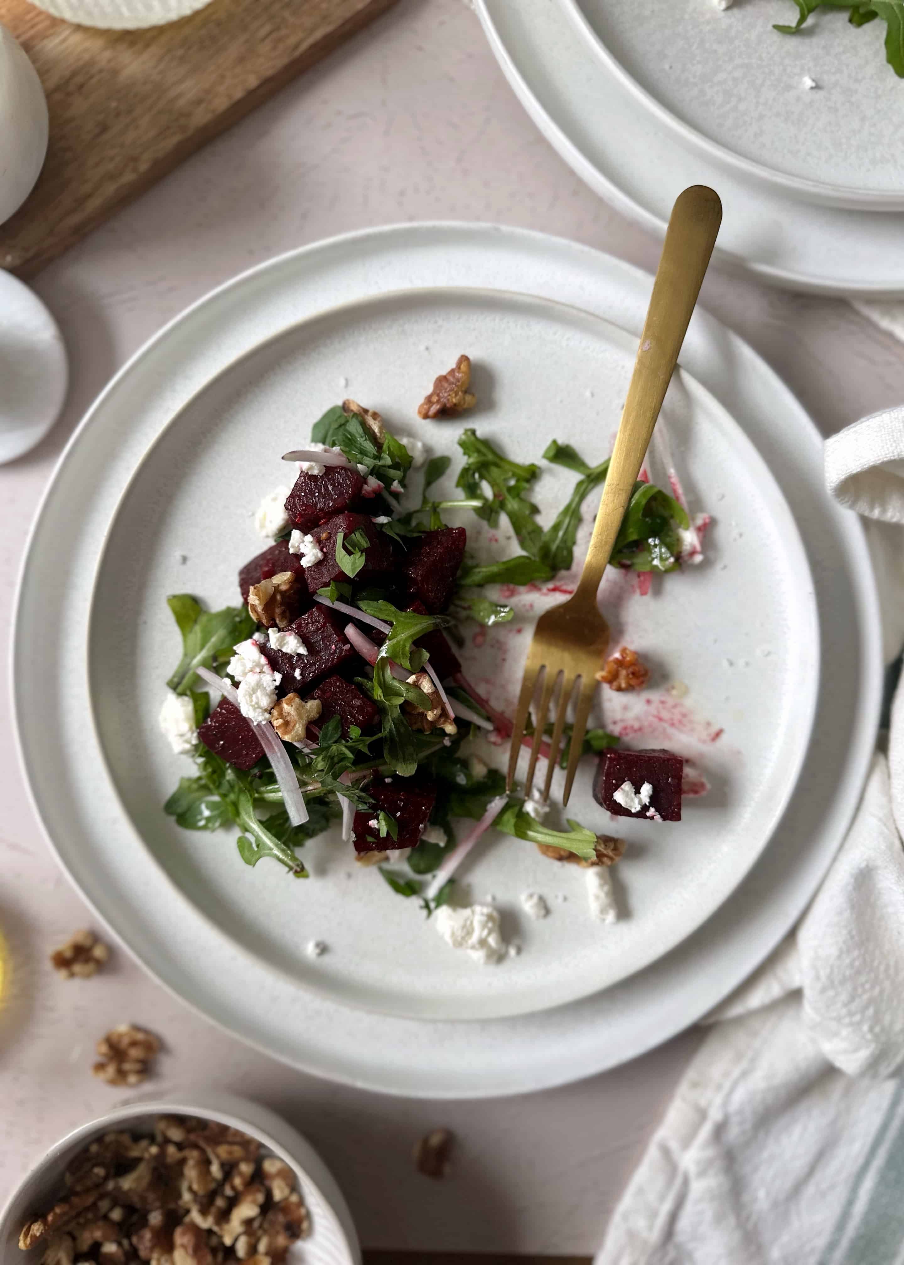 beetroot feta and walnut salad on white plate with gold fork