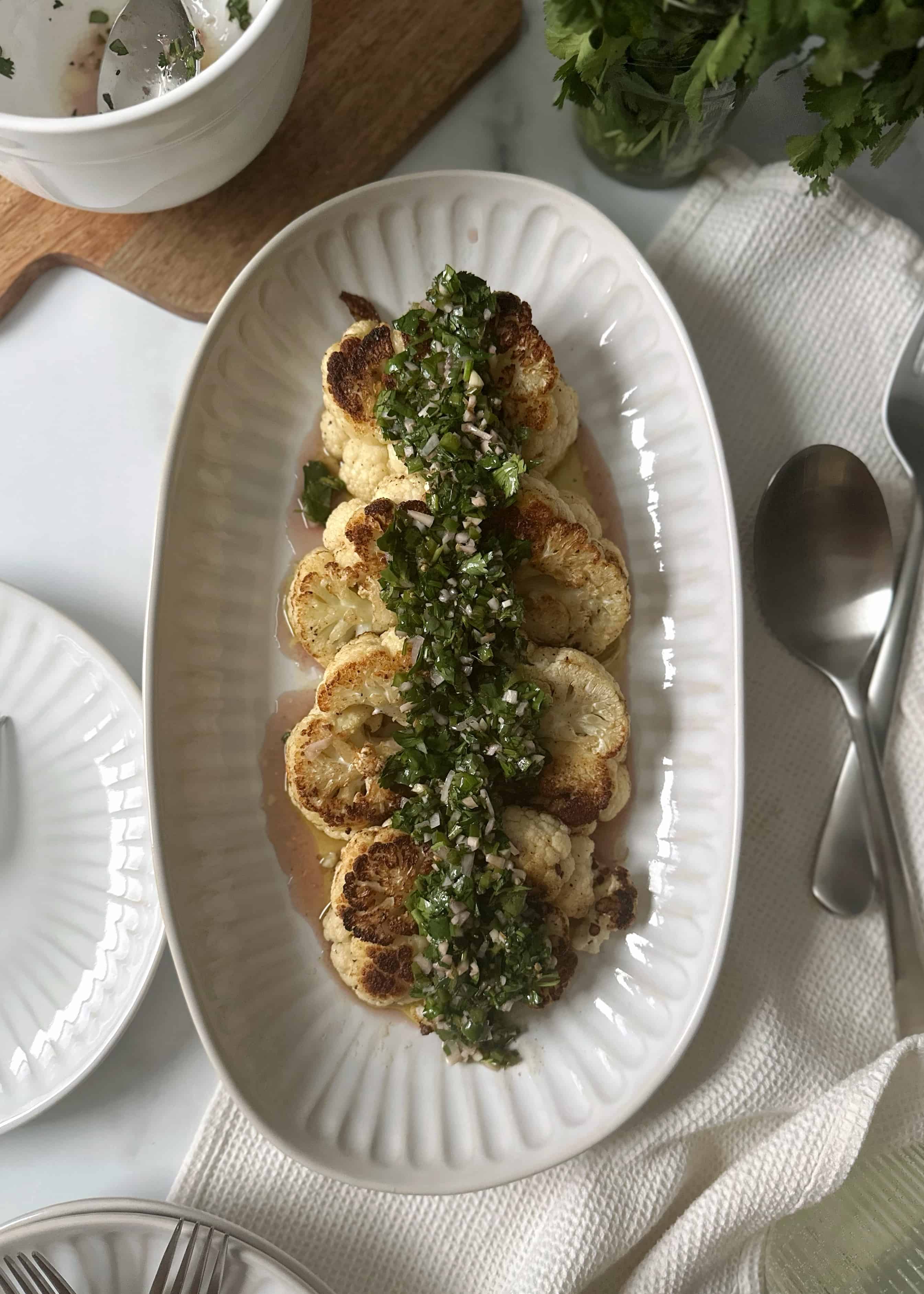 cauliflower steaks with green chimichurri on serving tray
