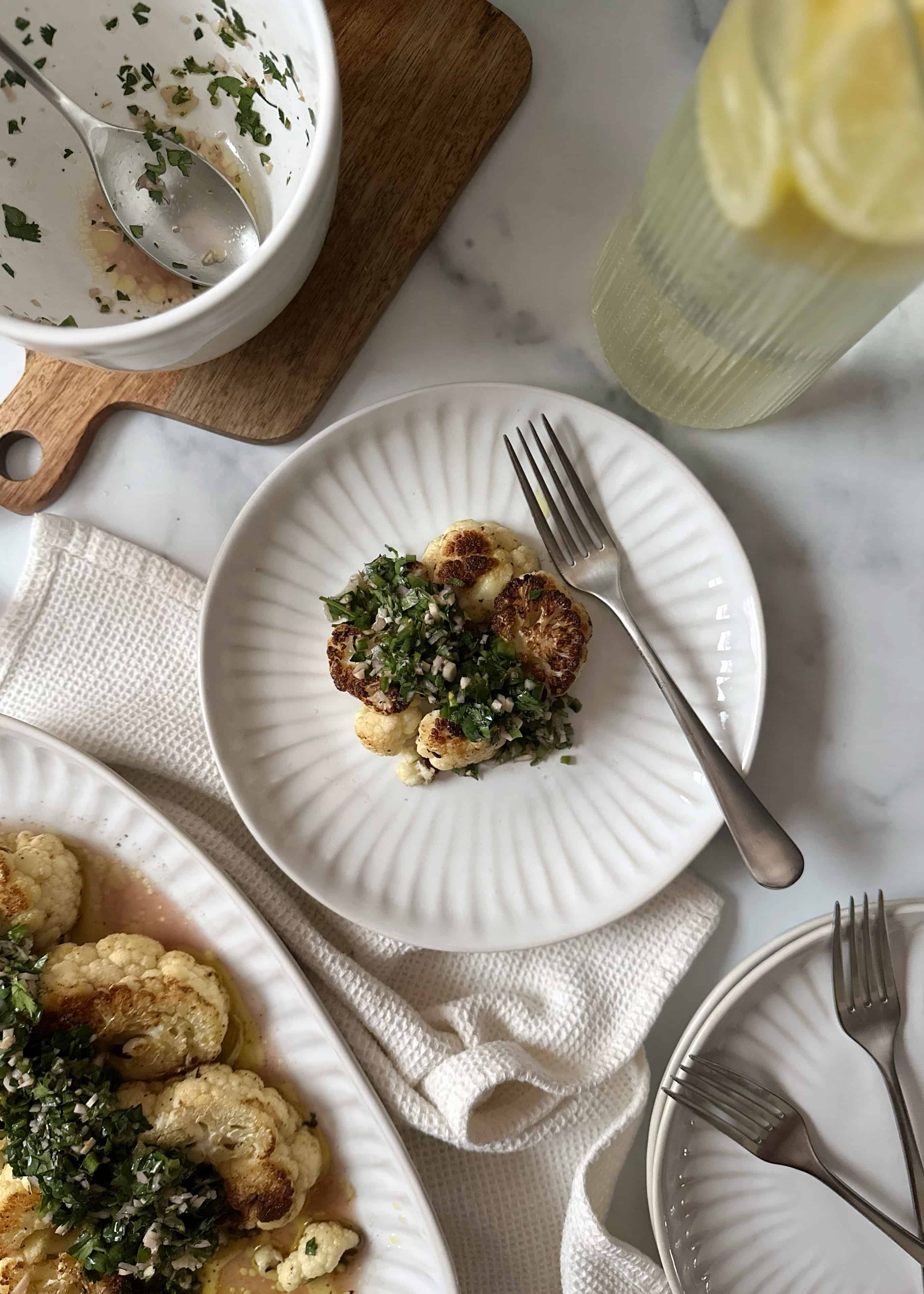 serving of cauliflower steaks with green chimichurri on white plate