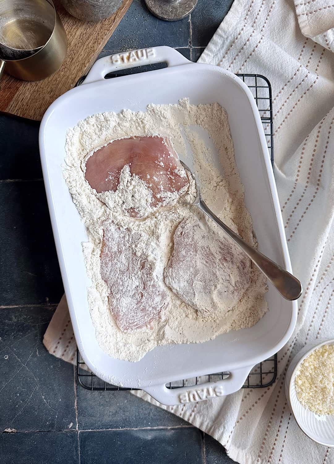 dredging chicken in flour in a pan