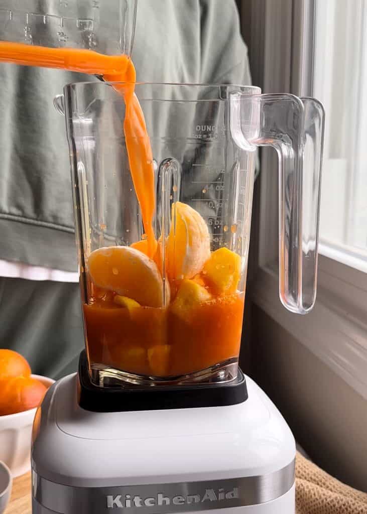 pouring carrot juice into orange mango smoothie