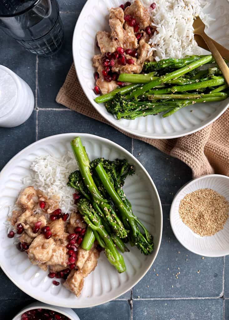 two bowls of chicken with pomegranate sauce and sesame broccolini