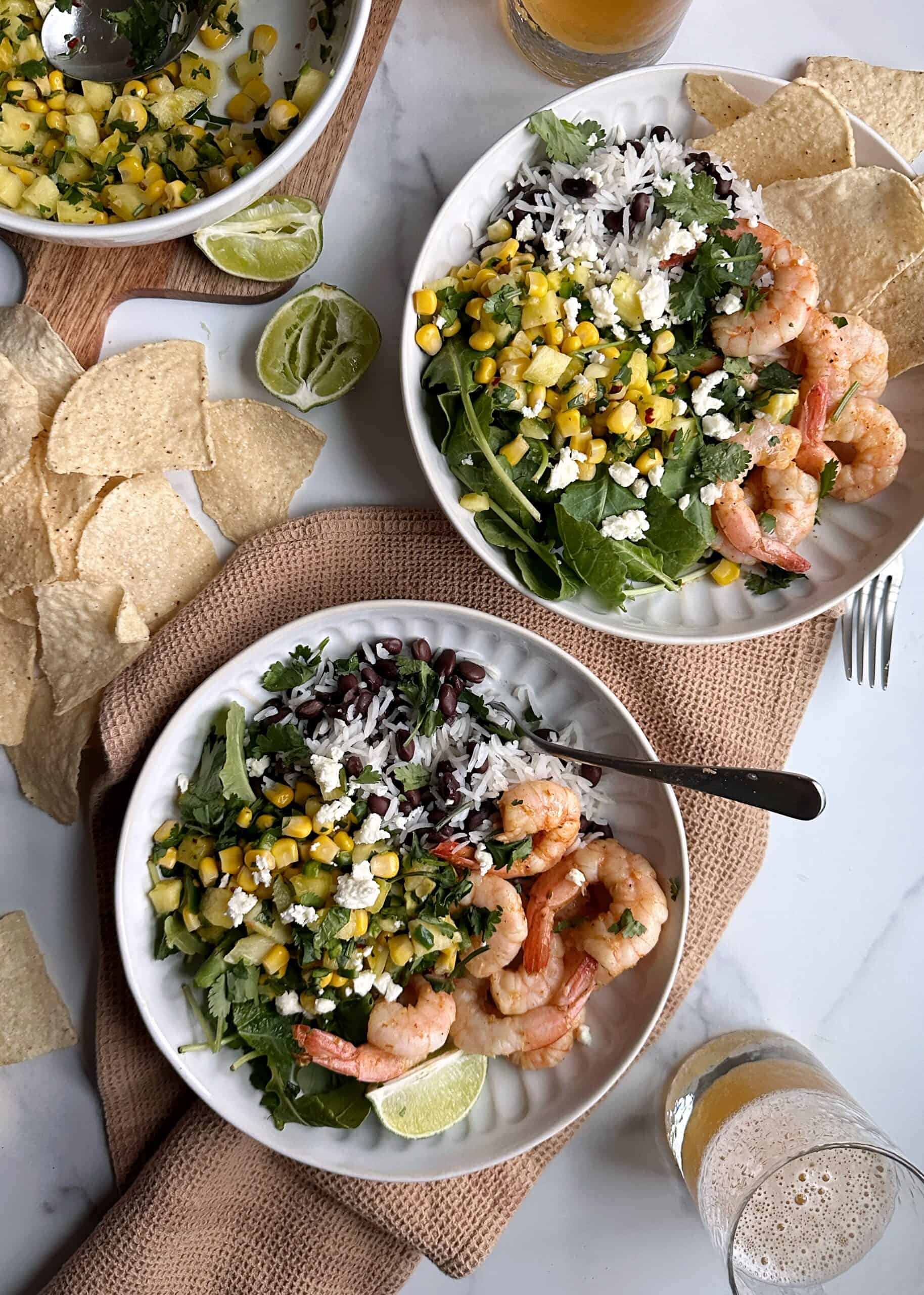 two shrimp burrito bowls with pineapple corn salsa