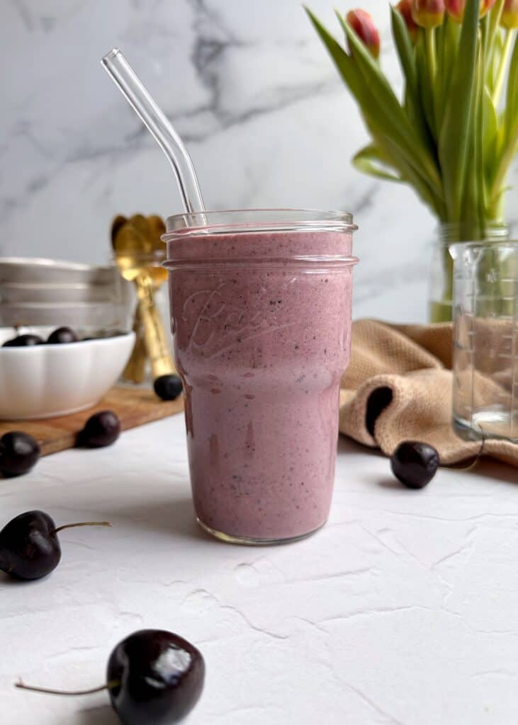 berry cherry smoothie in a glass with glass straw