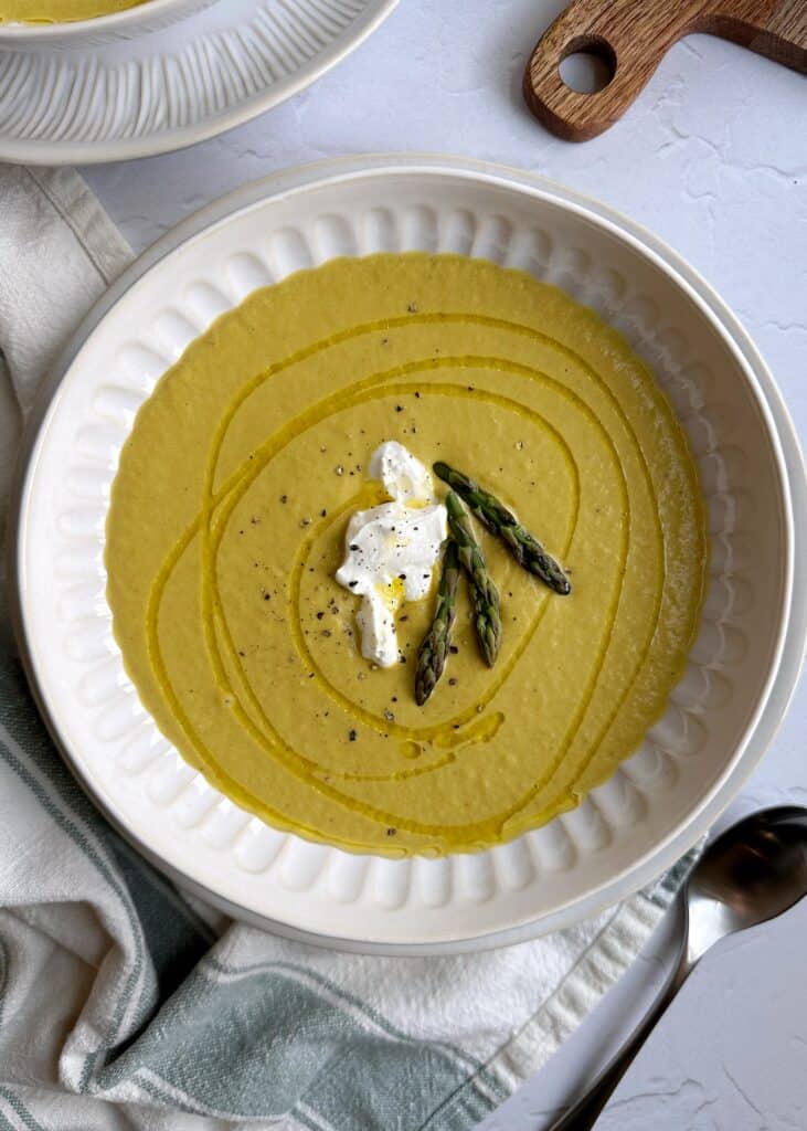 bowl of chilled asparagus soup with yogurt and asparagus top garnish