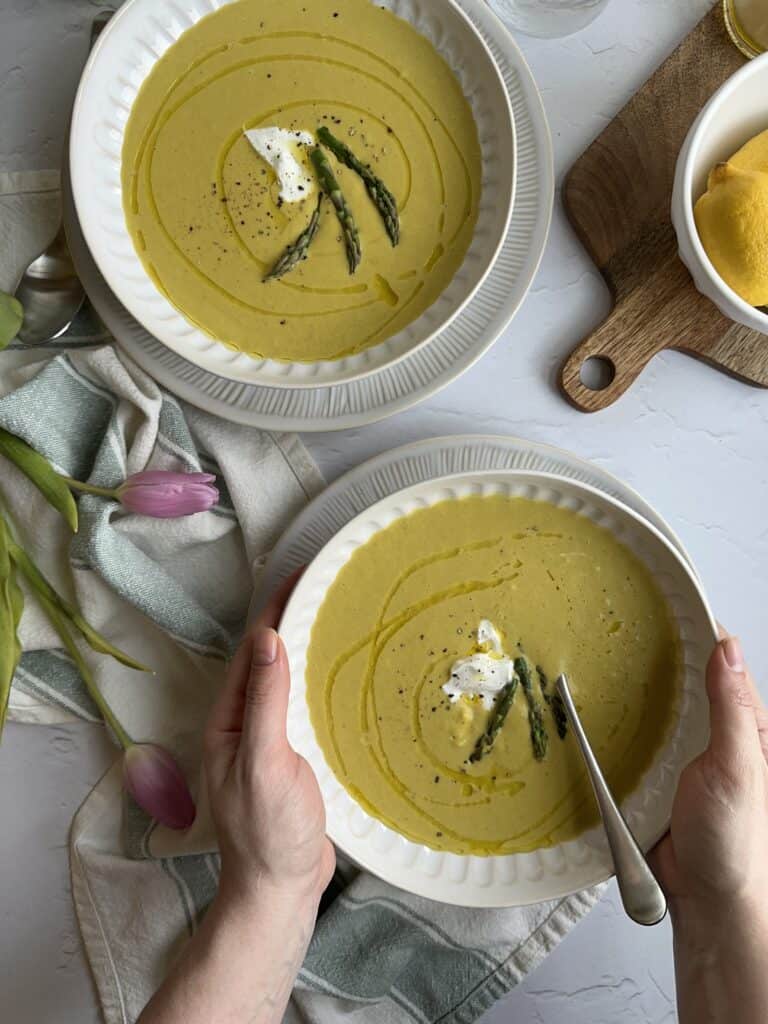 bowls of chilled asparagus soup with silver spoons