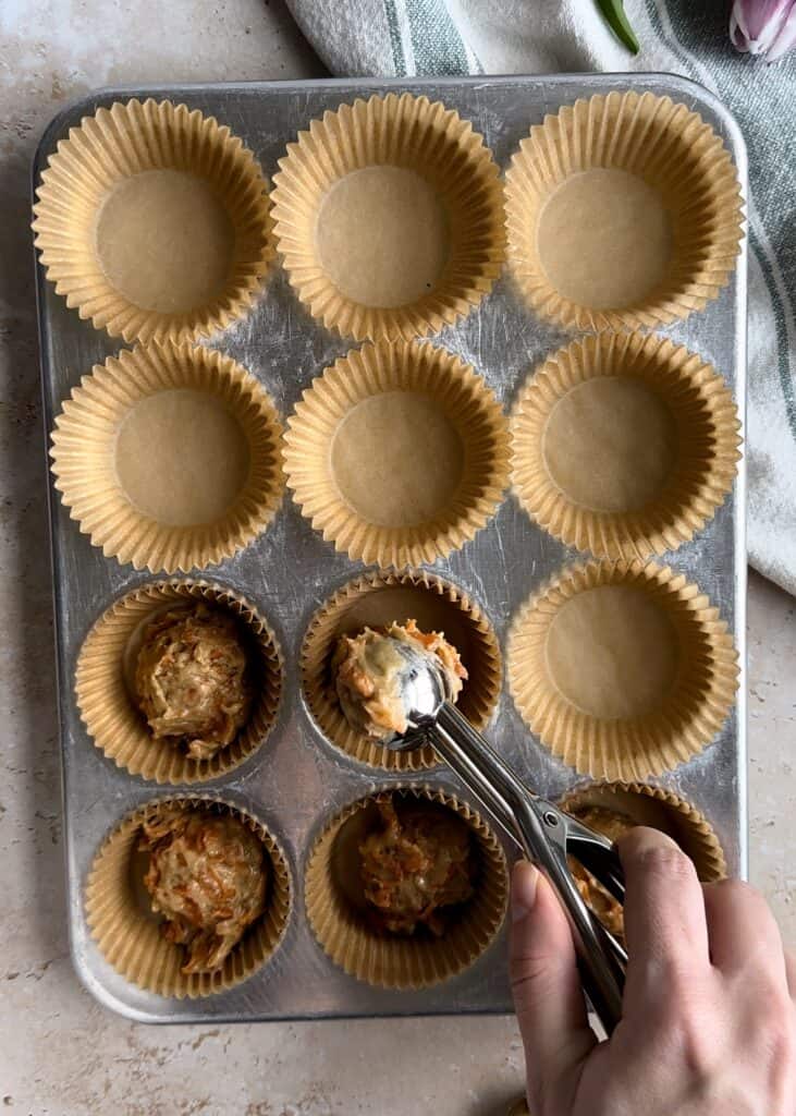 filling muffin tin with carrot muffin batter