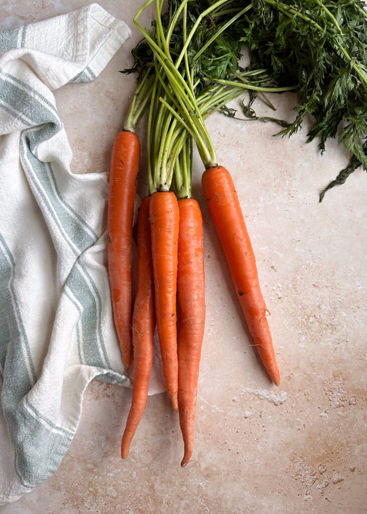 group of raw carrots with green tops