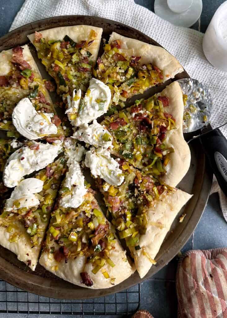 slices of leek bacon burrata pizza on tray