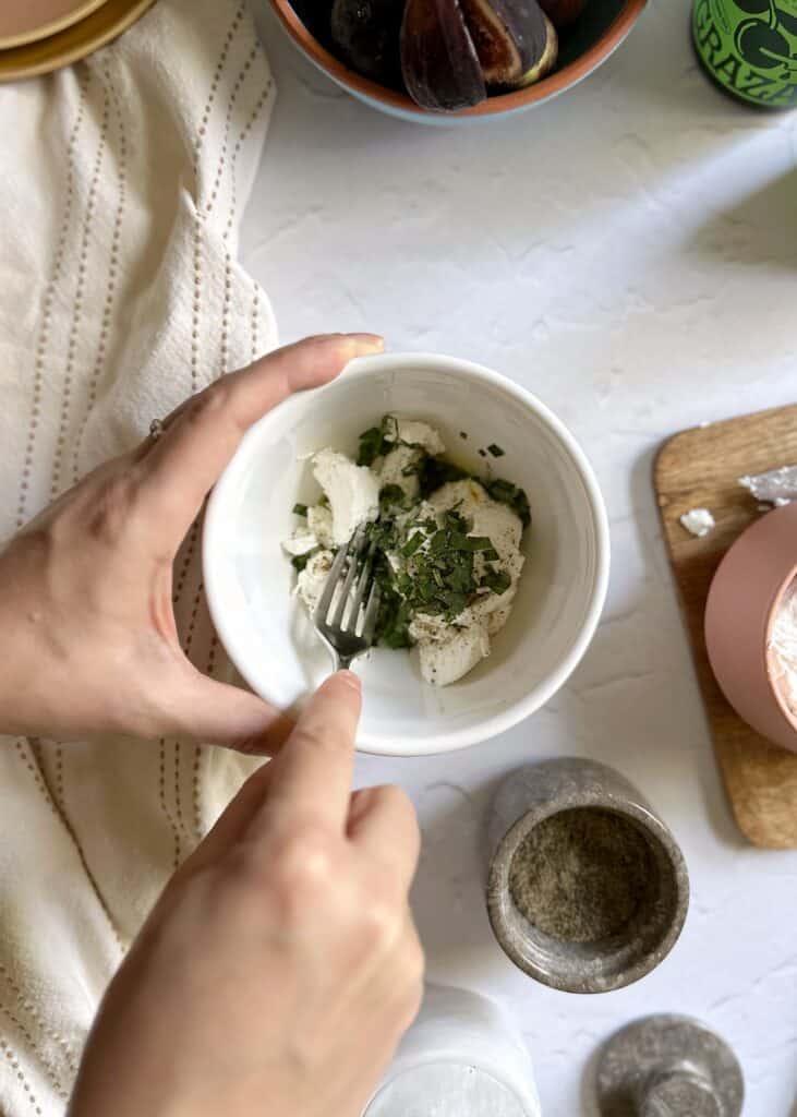 goat cheese with basil and olive oil in a white bowl