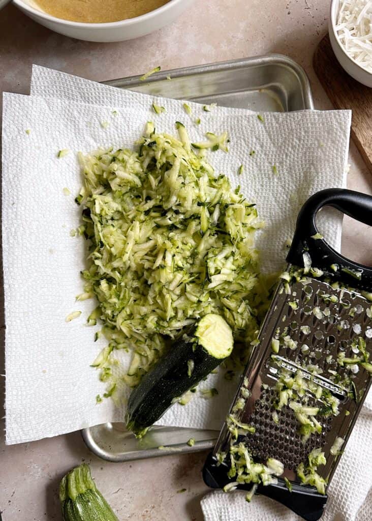 shredded zucchini on paper towel lined tray