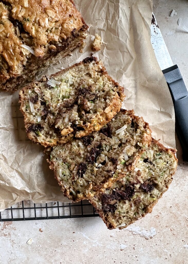 slices of zucchini bread with oatmeal coconut and chocolate chips on a cooling rack