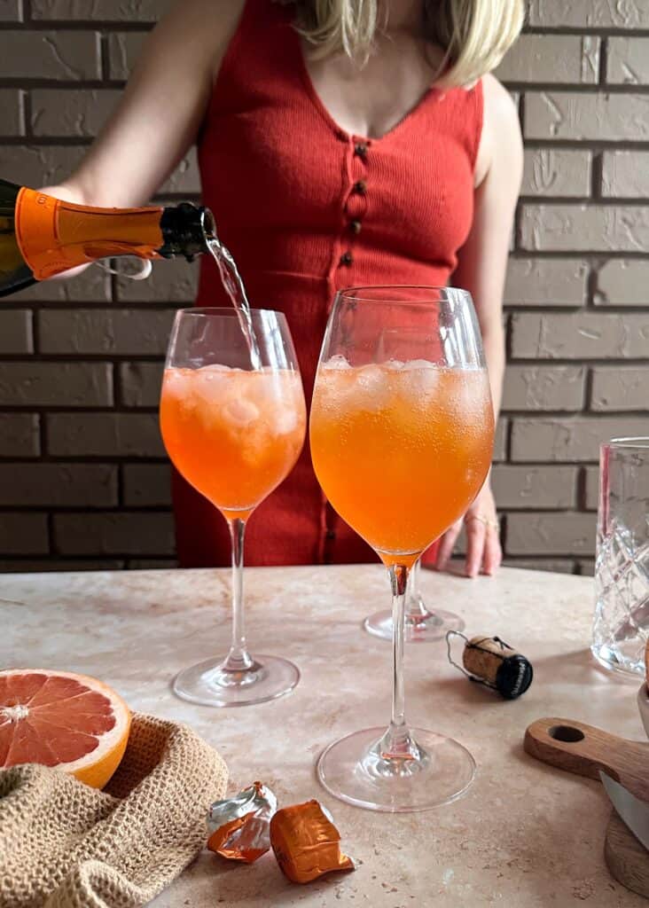 topping off an aperol paloma spritz with prosecco