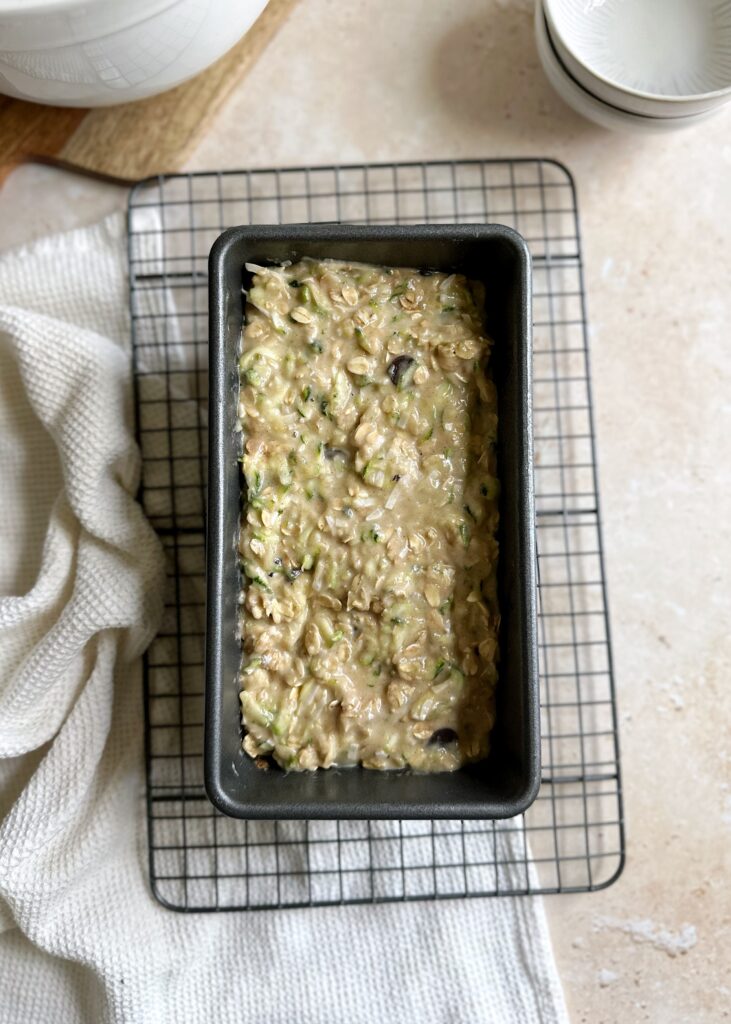 zucchini bread batter in a baking tin on a rack