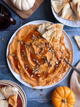 pumpkin hummus with pita chips on the side and toasted pumpkin seeds