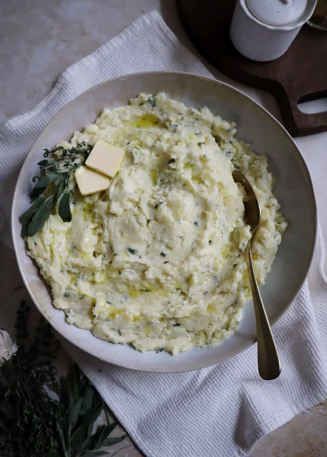 bowl of buttery garlic and herb mashed potatoes with golden spoon