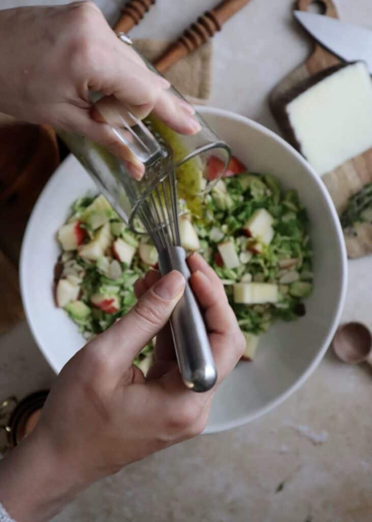 pouring vinaigrette over brussels sprouts salad