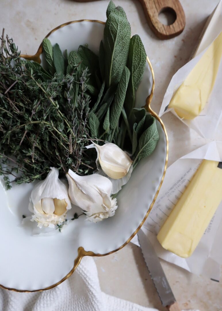 sage thyme and garlic in a white bowl with butter on the side