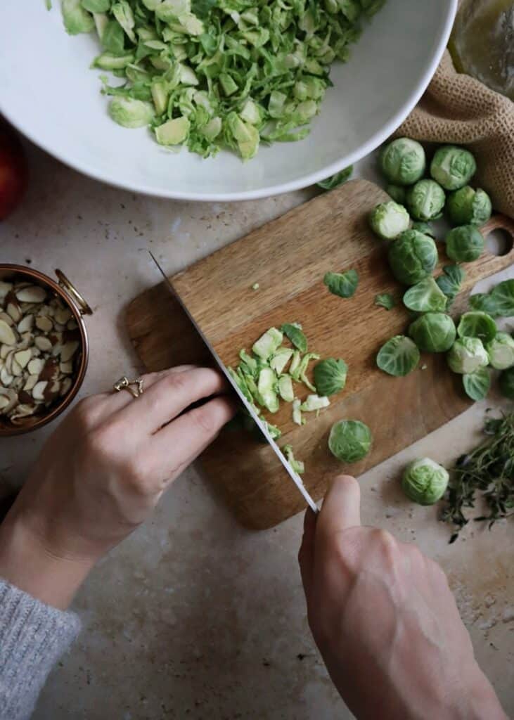 shaving brussels sprouts on wooden cutting board