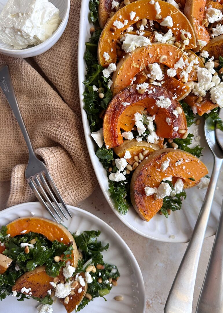 platter of butternut squash kale salad feta and pine nuts with plate on the side