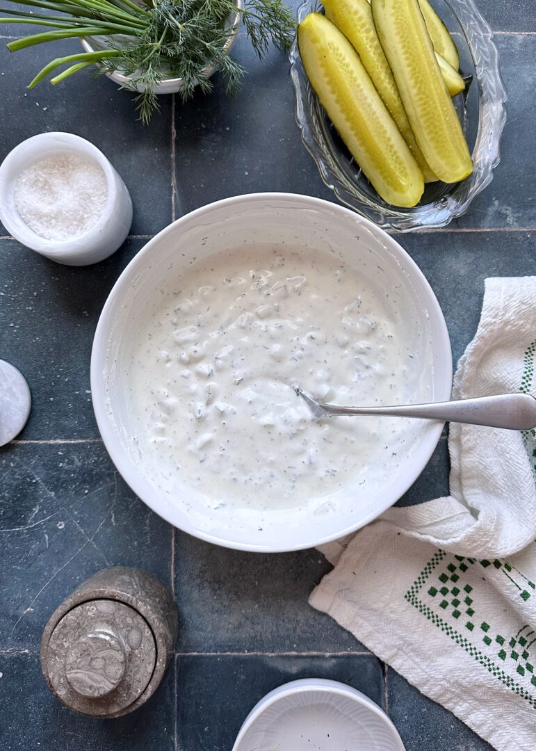 dill pickle ranch dressing in white mixing bowl with silver spoon