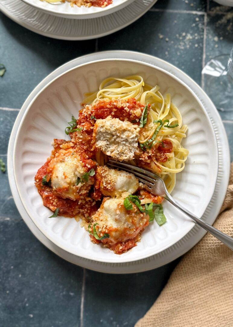 bowl of chicken parmesan meatballs and pasta with a fork