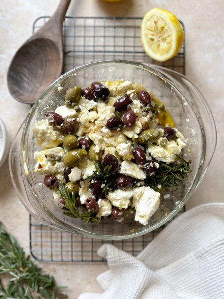 feta and olives marinating in a glass bowl