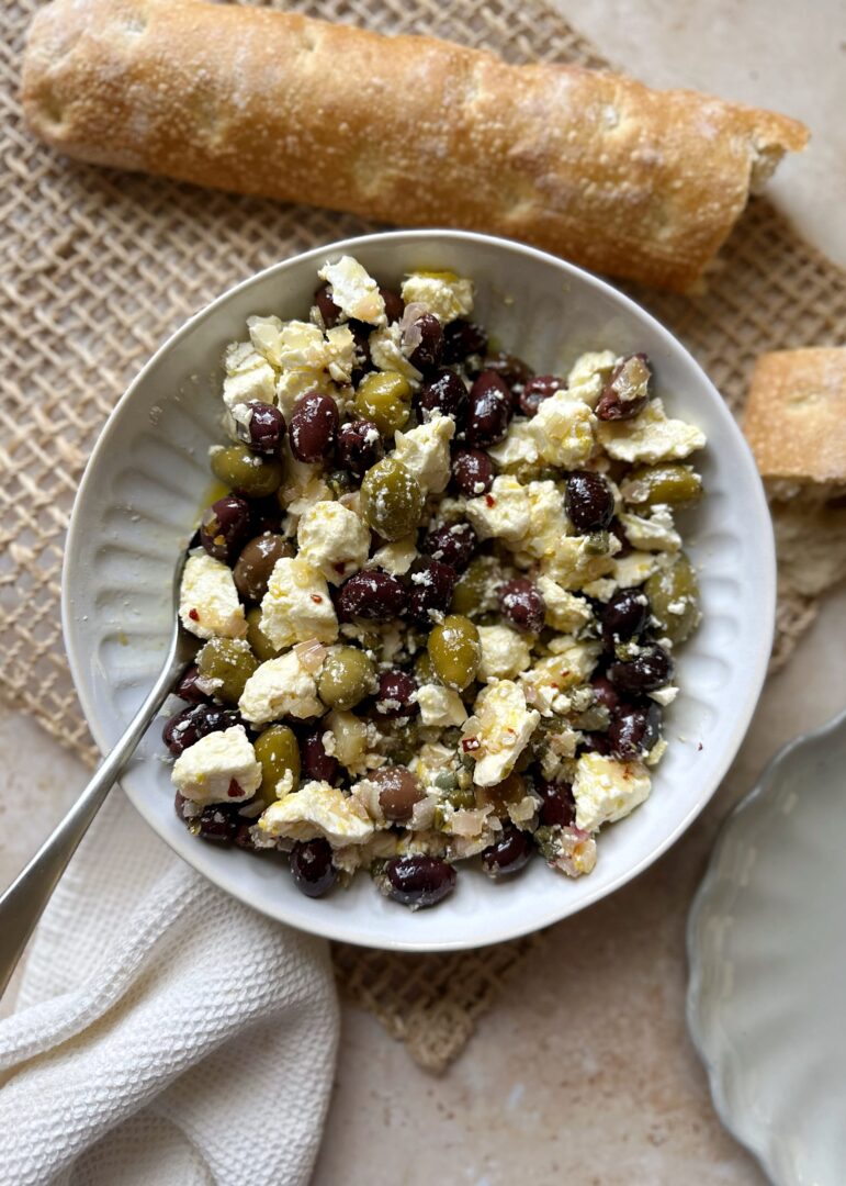 serving bowl of marinated olives and feta with a side of bread