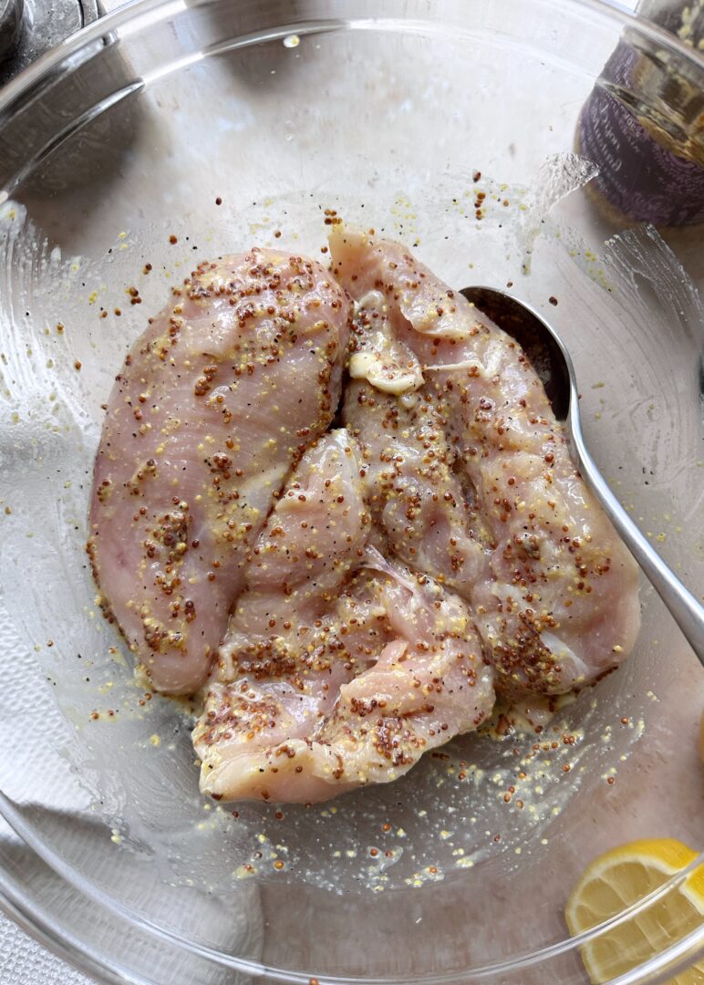 chicken in a glass bowl marinating in lemon marinade
