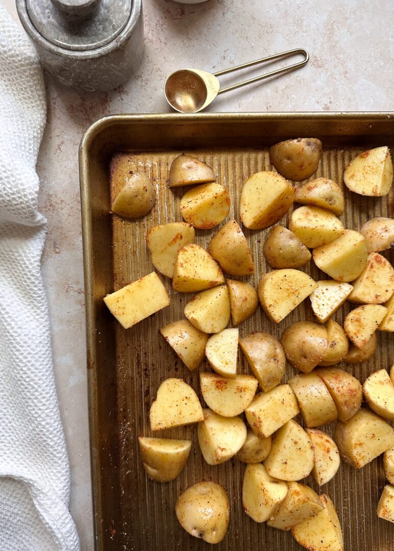 cubed and seasoned golden potatoes on a baking sheet