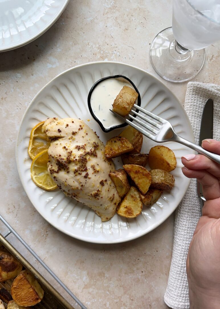 plate of lemon chicken and dipping a potato wedge in ranch
