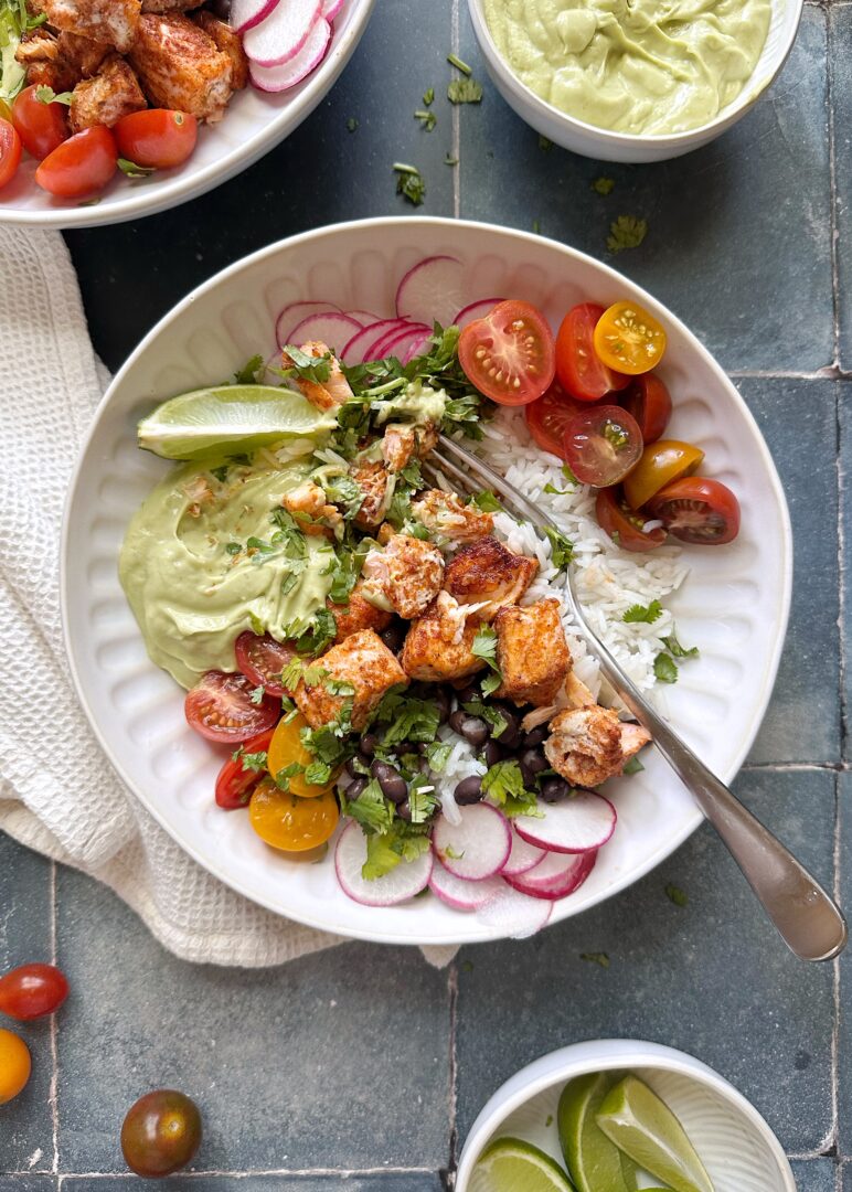 salmon burrito bowl with avocado crema with silver fork