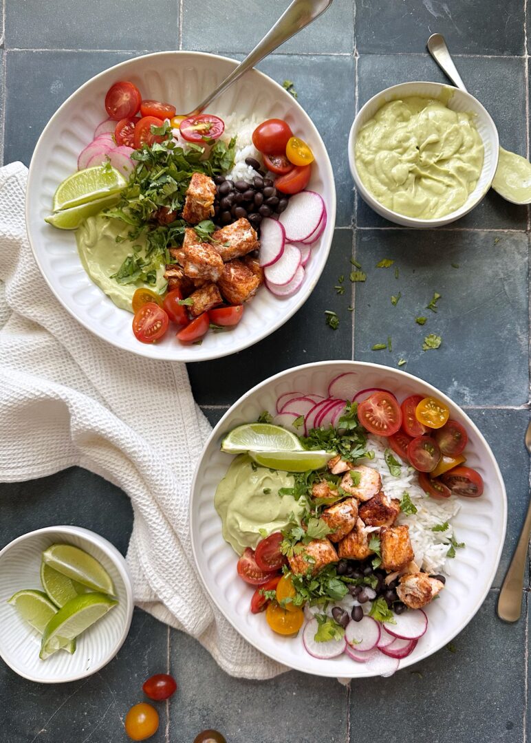 two bowls of salmon burrito bowls with avocado crema
