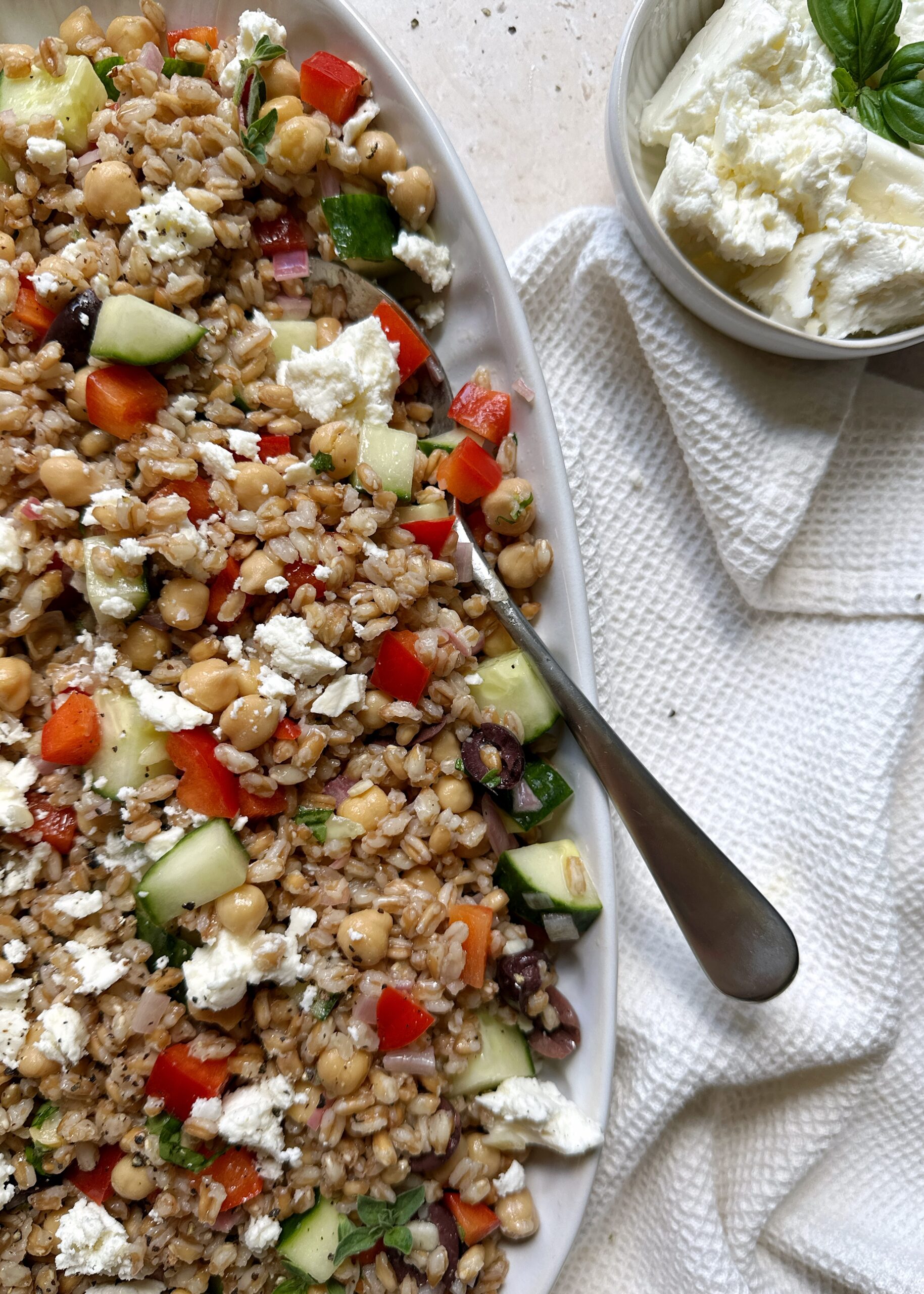 serving bowl of greek farro salad with a silver spoon