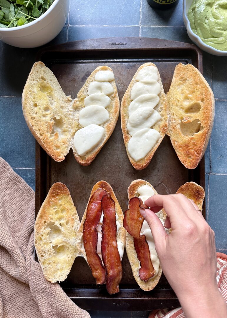 adding bacon to sandwiches with melted mozzerella
