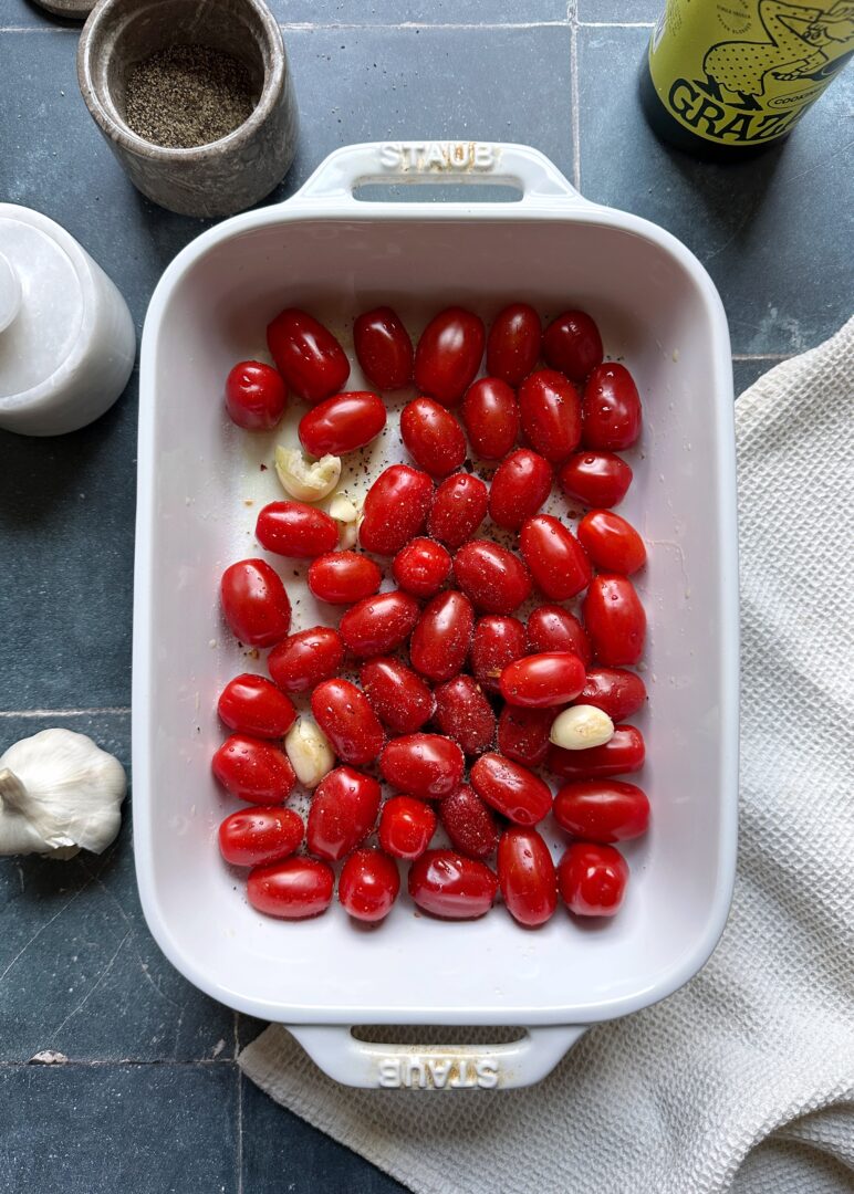 grape tomatoes in a casserole dish with garlic cloves