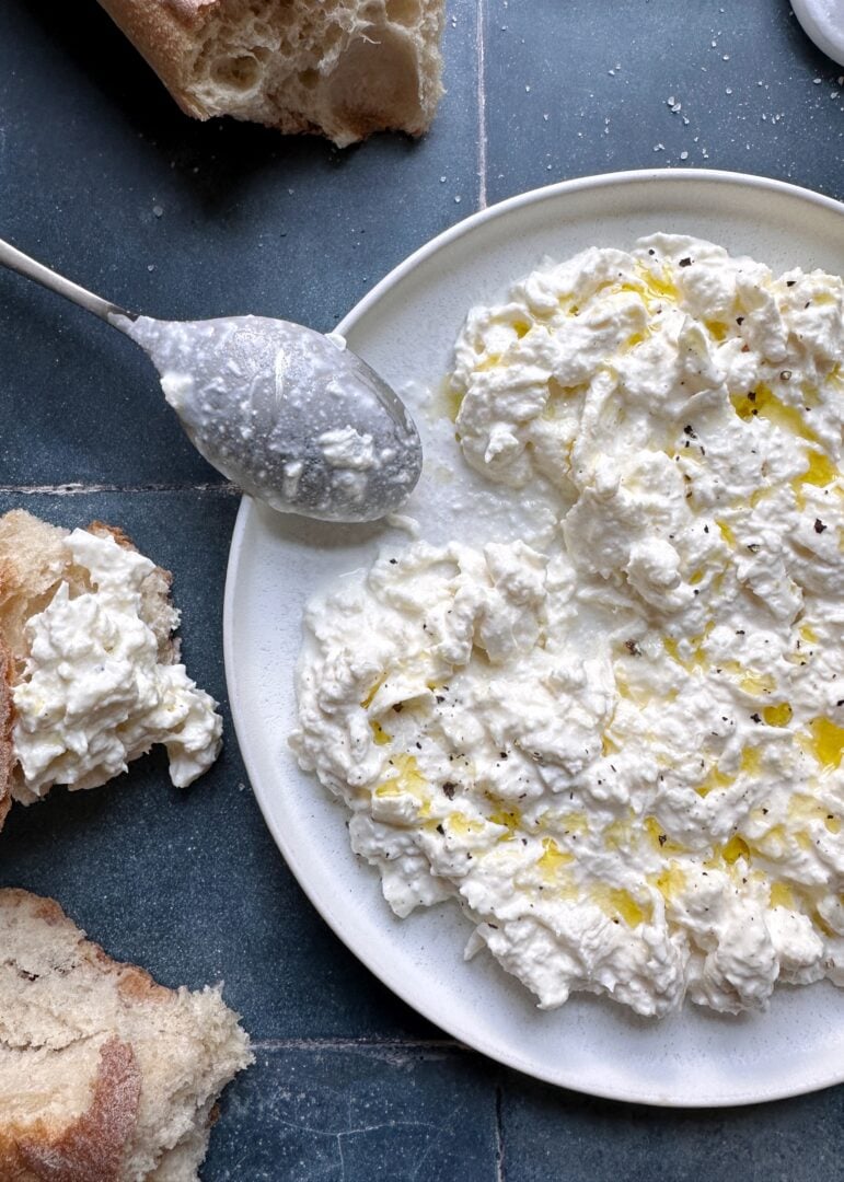 homemade stracciatella cheese on a plate with silver spoon