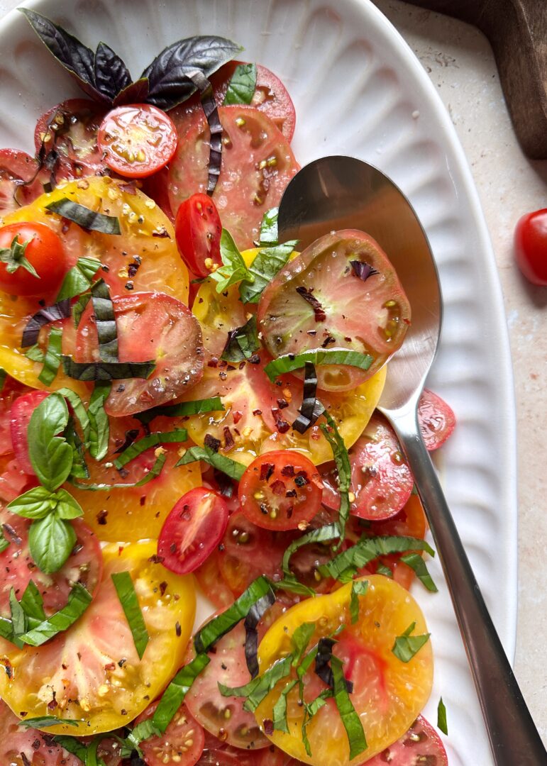 plate of mixed tomato salad with silver serving spoon