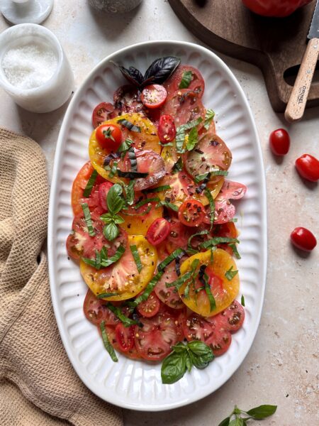 serving platter of mixed tomato salad with fresh basil garnish