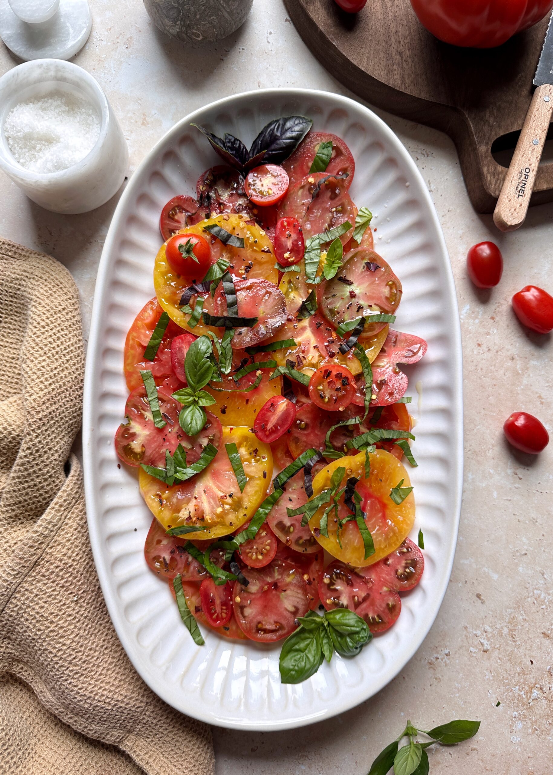 serving platter of mixed tomato salad with fresh basil garnish