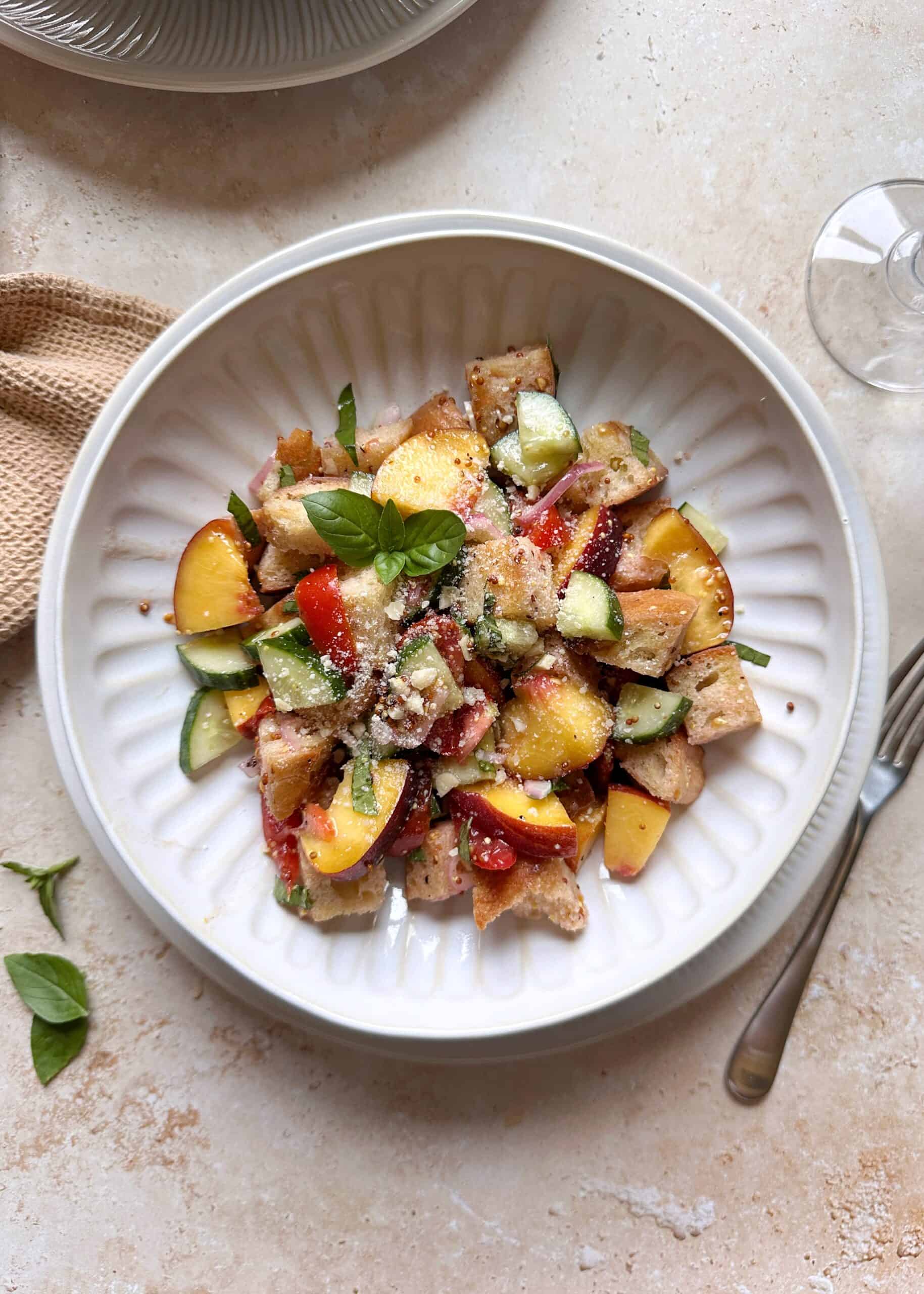 tomato cucumber peach panzanella salad with grated parmesan
