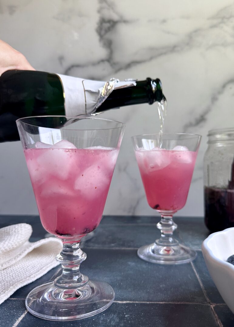 topping off blueberry mules with champagne