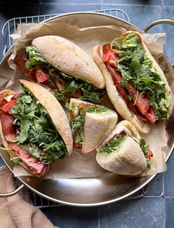 tray of green goddess caprese melt sandwiches with bacon and arugala