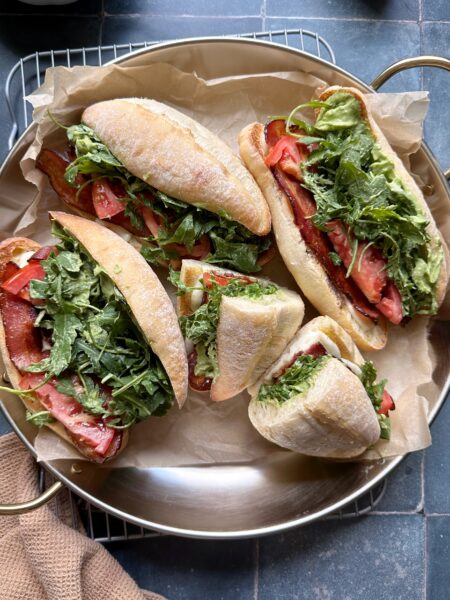tray of green goddess caprese melt sandwiches with bacon and arugala