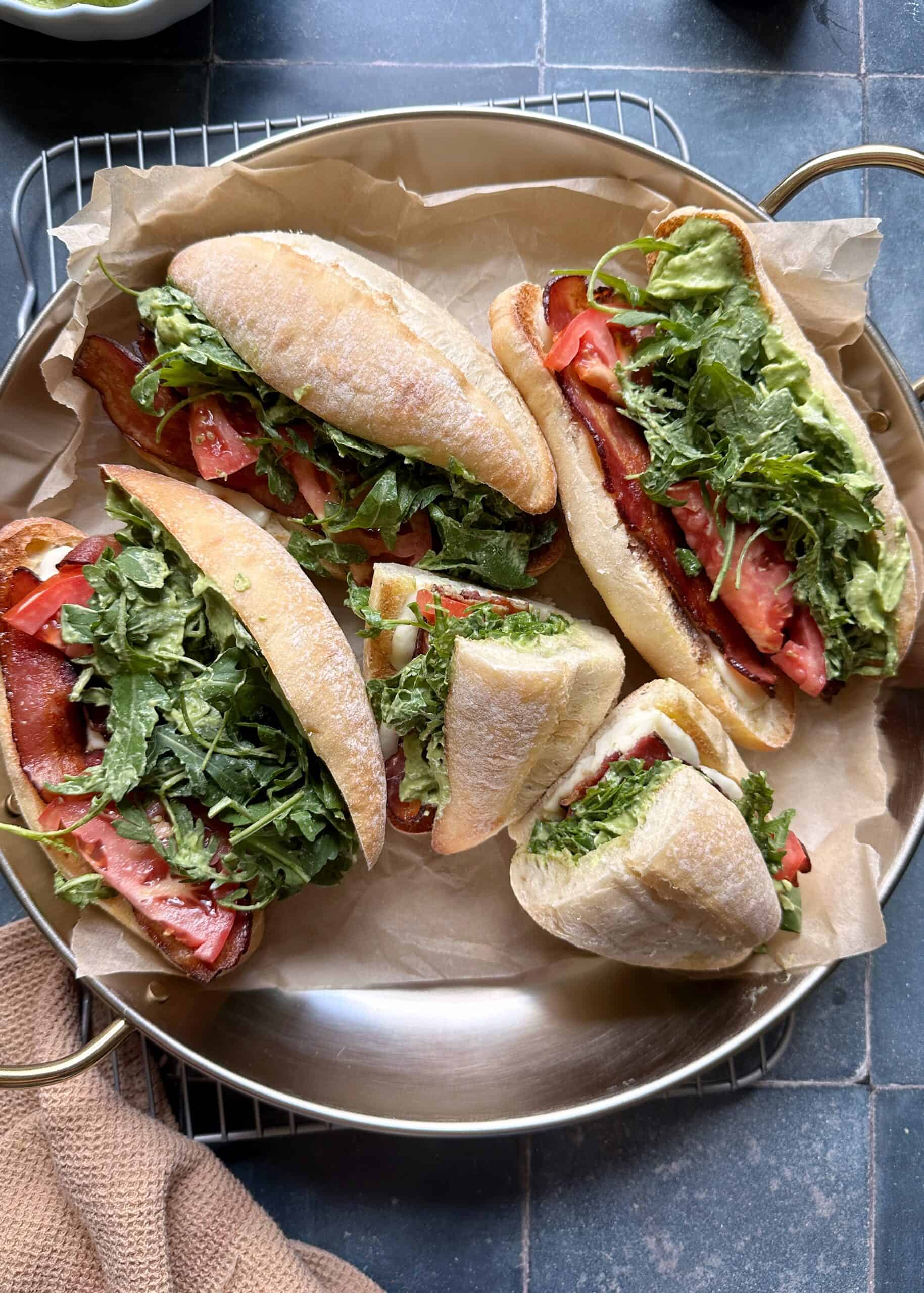 tray of green goddess caprese melt sandwiches with bacon and arugala