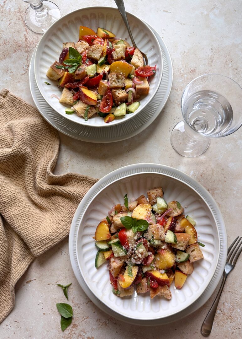 two bowls of tomato cucumber and peach panzanella salad
